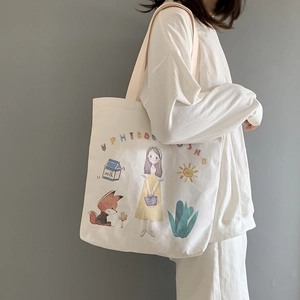 Detail of white canvas tote bag with colorful cartoon illustrations and soft fabric texture