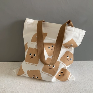 Détail d'un sac cabas en toile blanche avec motifs de biscuits et anses tressées