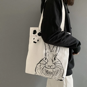 Detailed texture of white canvas tote bag with rabbit print and panda plush pendant