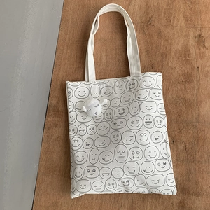 Detailed view of white canvas tote bag with cartoon print and plush lamb charm accessory
