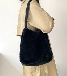 Vue latérale d'un sac cabas en peluche noire porté avec un trench-coat élégant