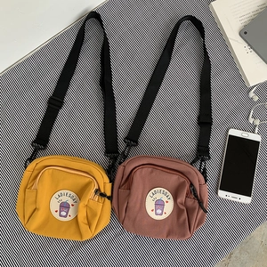 Detalle de bolsos bandolera de lona amarillos y marrones con correas de nailon y parches