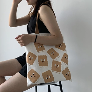 Détail du sac fourre-tout en toile blanche avec motifs de biscuits et texte imprimé