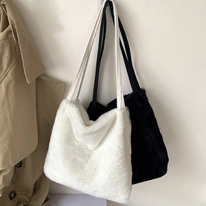 Vue détaillée de sacs cabas en fausse fourrure douce blancs et noirs sur un mur