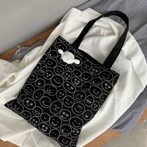 Black canvas tote bag with white cartoon expression prints and cute sheep plush pendant