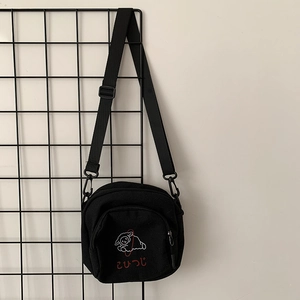 Détail du sac bandoulière en toile noire avec broderie d'agneau et texte japonais