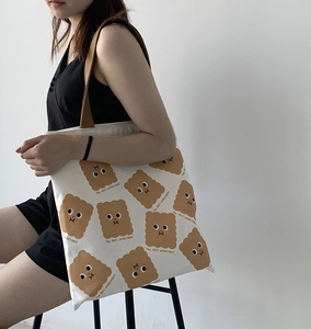 Détail du sac cabas en toile avec imprimés biscuits mignons et bandoulières en tissu brun