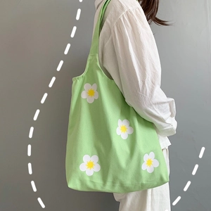 Close-up of light green canvas tote bag featuring white daisy prints and fabric texture