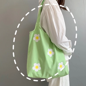 Detail view of light green canvas shoulder bag featuring small white daisy patterns