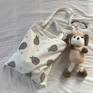 Vue détaillée du sac cabas en toile avec motif d'ananas violet sur surface en tissu blanc