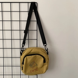 Détail du sac bandoulière en toile jaune avec imprimé mouton et sangle réglable