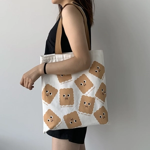 Détail du sac cabas en toile blanche avec motif biscuit et sangle marron sur modèle