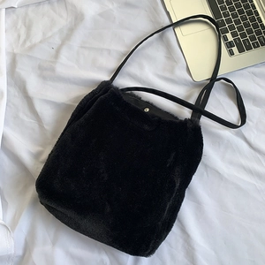Détail de la texture douce du sac bandoulière en fausse fourrure noire avec bouton pression