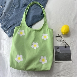 Detailed close-up of grass green floral canvas tote bag with white flower patterns