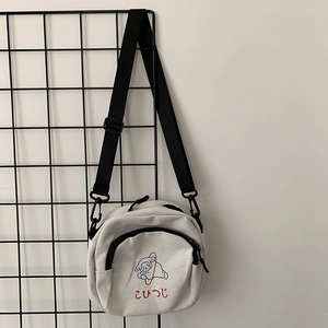 Détail de la bandoulière noire réglable et de l'imprimé mouton sur le sac en toile blanc cassé