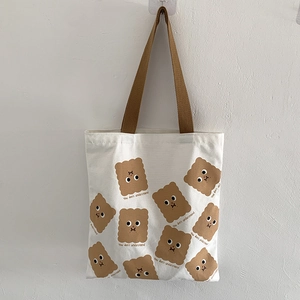 Détail du sac cabas en toile blanche avec motifs biscuits et anses marron foncé