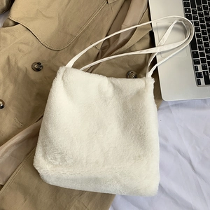 Détail d'un sac cabas en fausse fourrure blanche posé sur un trench-coat élégant