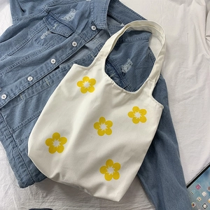 Detailed texture of white canvas bag featuring printed yellow flower patterns on denim
