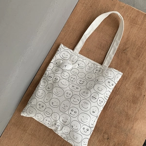 Close-up of canvas tote bag with funny face patterns and 3D plush animal charm detail