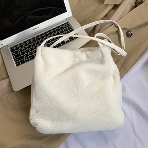 Gros plan d'un sac à bandoulière blanc en fausse fourrure pelucheuse sur un portable