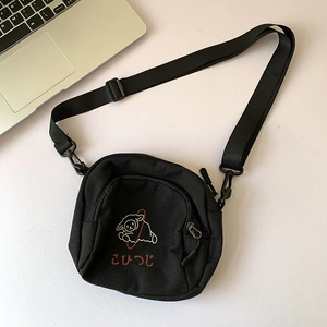 Détail du sac bandoulière en toile noire avec imprimé mouton blanc et texte japonais