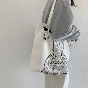 Close-up of white canvas tote bag featuring cute rabbit print and panda plush charm