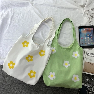 Detail of white and green canvas tote bags with minimalist yellow floral print