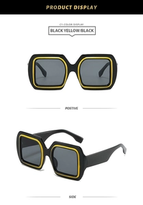 Detail view of square oversized sunglasses with black frame and yellow inner accent line