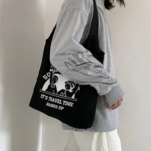 Side view of black canvas tote bag featuring white travel illustration and shoulder strap