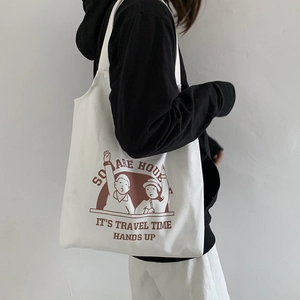 Close-up of a cream canvas tote bag featuring vintage red cartoon prints and typography