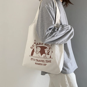Close-up of cream canvas tote bag featuring vintage brown illustration and travel text