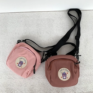 Detalle de bolsos bandolera de lona rosa y malva con parche Ladiesday y cierre de zip