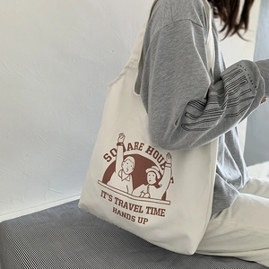 Detail of the large canvas tote bag featuring cute cartoon graphics and shoulder strap