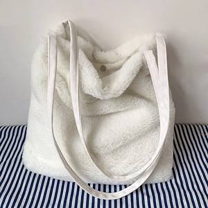 Vue détaillée d'un sac cabas en fausse fourrure blanche montrant le fermoir magnétique