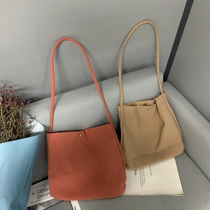 Minimalist nylon canvas tote bags in red and khaki colors on a soft fabric sofa