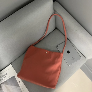 Detail view of red nylon canvas tote bag with metal button closure and long strap