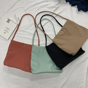 Flat lay of colorful nylon tote bags in brick red, mint green, black and khaki