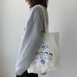Detail of white canvas shoulder bag with Japanese cartoon illustration on a model