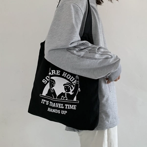 Black canvas tote bag with white graphic print for women shown in a casual shoulder wear style