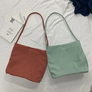 Detail of candy-colored nylon tote bags in brick red and mint green with magnetic snaps