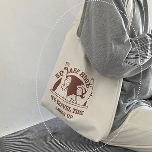 Side view of a large cream canvas tote bag with vintage cartoon print worn by a model