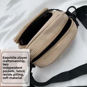 Close-up of khaki crossbody bag featuring double zip pockets and soft nylon fabric