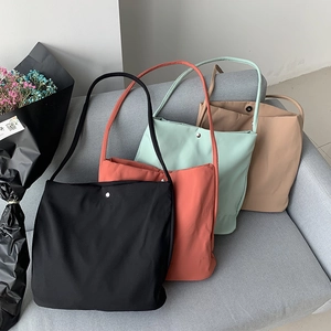 Detail view of simple canvas tote bags in four colors arranged on a soft grey sofa