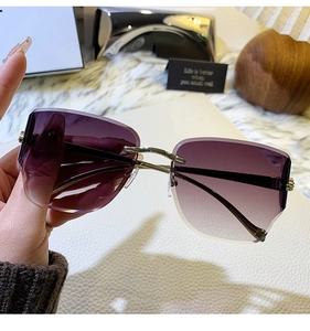Détail de lunettes de soleil sans monture dégradé violet avec accents léopard dorés en main