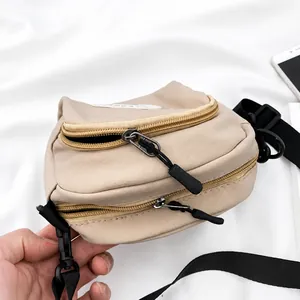 Detail of beige nylon crossbody bag showing multi-layer zippers and black rope pullers