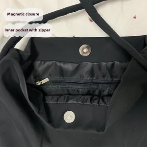 Detail of black nylon canvas bag featuring a secure magnetic snap closure and zipper pocket