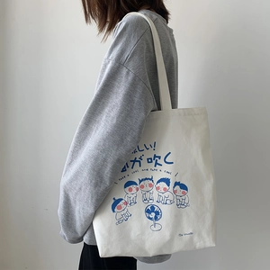 Detail view of canvas tote bag showing cute blue cartoon characters and Japanese text