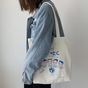Detail of white canvas tote bag with blue Japanese cartoon graphics and smooth fabric texture