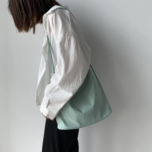 Detail of mint green minimalist nylon tote bag with wide shoulder strap on model