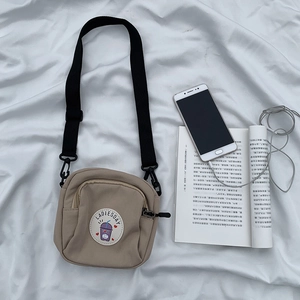 Vista plana de un bolso bandolera pequeño de lona con correa y parche decorativo
